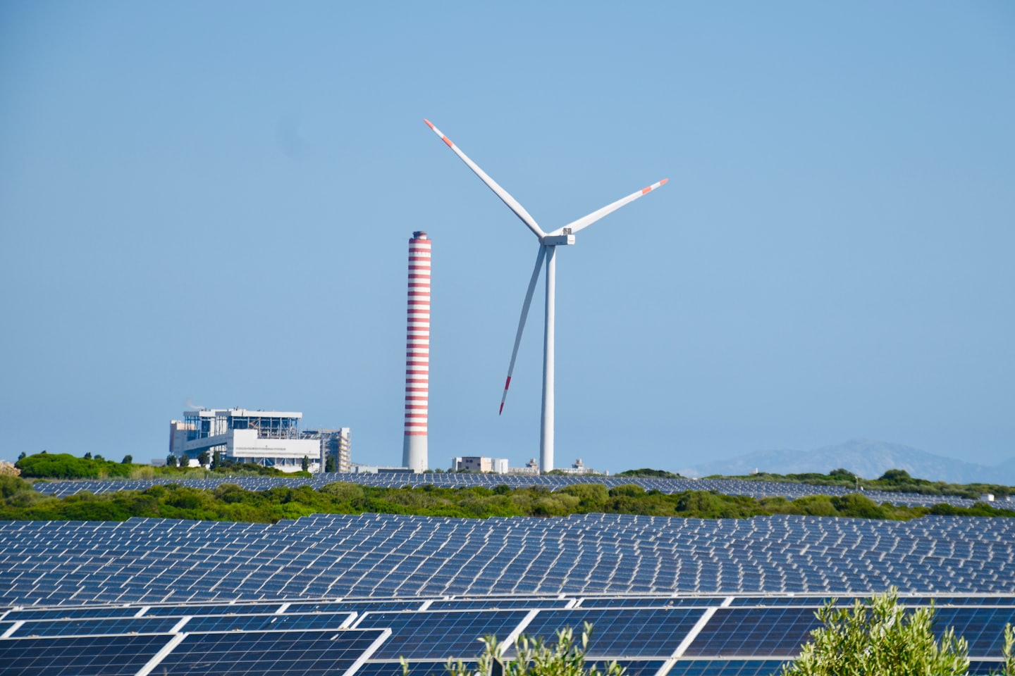Pannelli solari in un campo con un edificio e una turbina eolica.